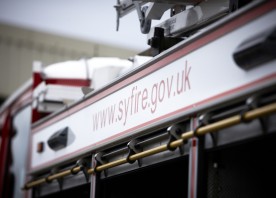 This picture shows the side of a fire engine. Specifically it shows a white strip above the three equipment lockers. The service's website address is written across the strip.