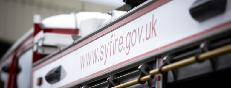 This picture shows the side of a fire engine. Specifically it shows a white strip above the three equipment lockers. The service's website address is written across the strip.