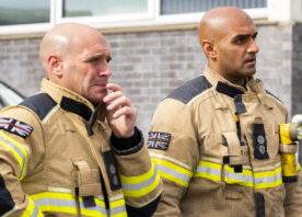 Two firefighters in fire kit watching training