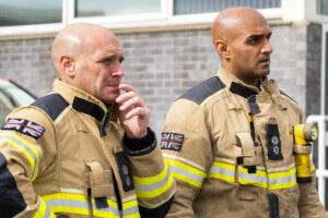 Two firefighters in fire kit watching training