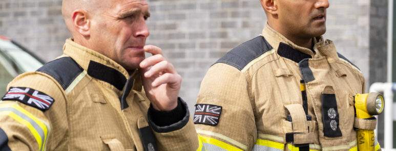 Two firefighters in fire kit watching training